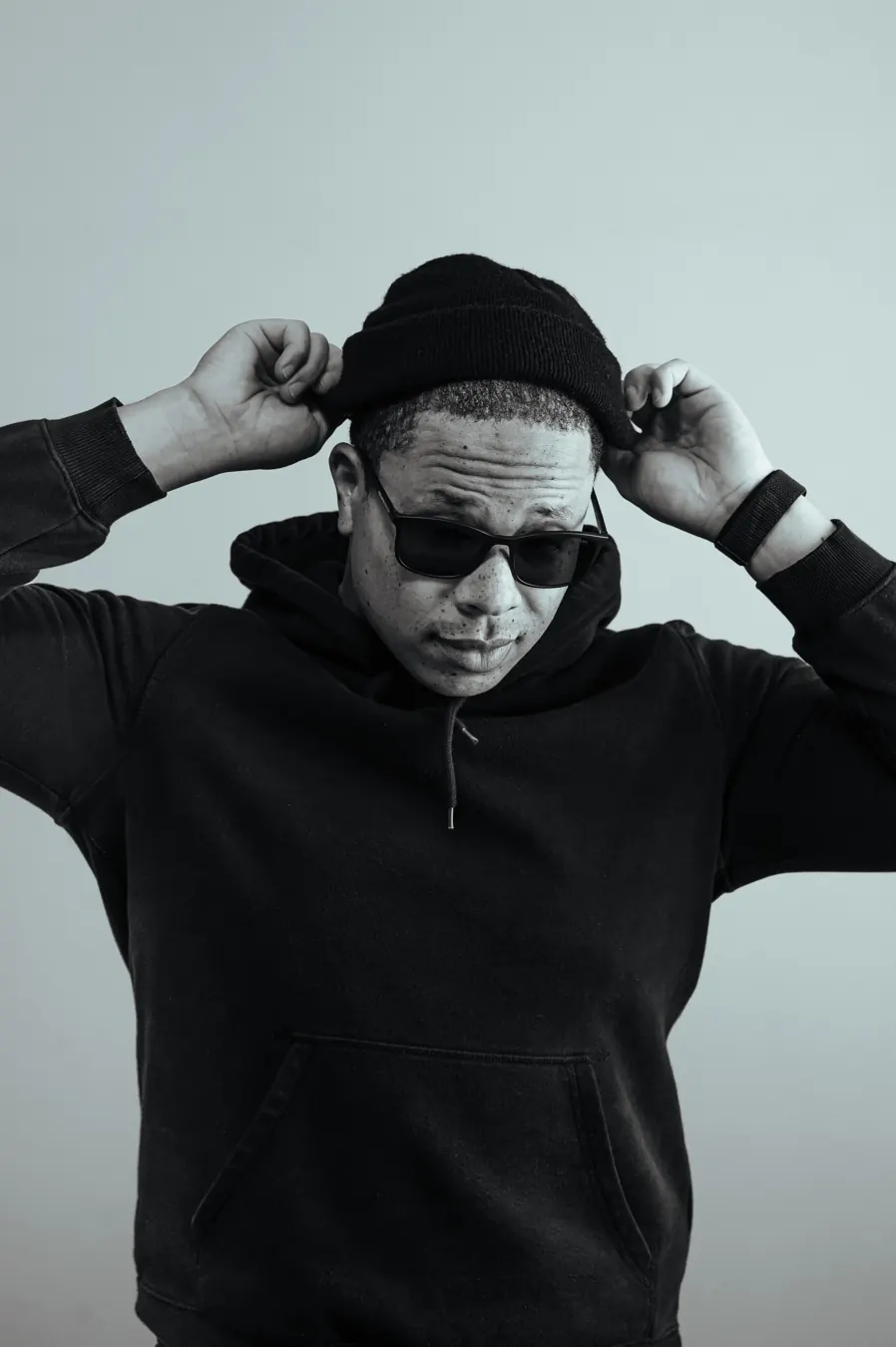 OKAY TK in sunglasses and a black beanie, black-and-white portrait
