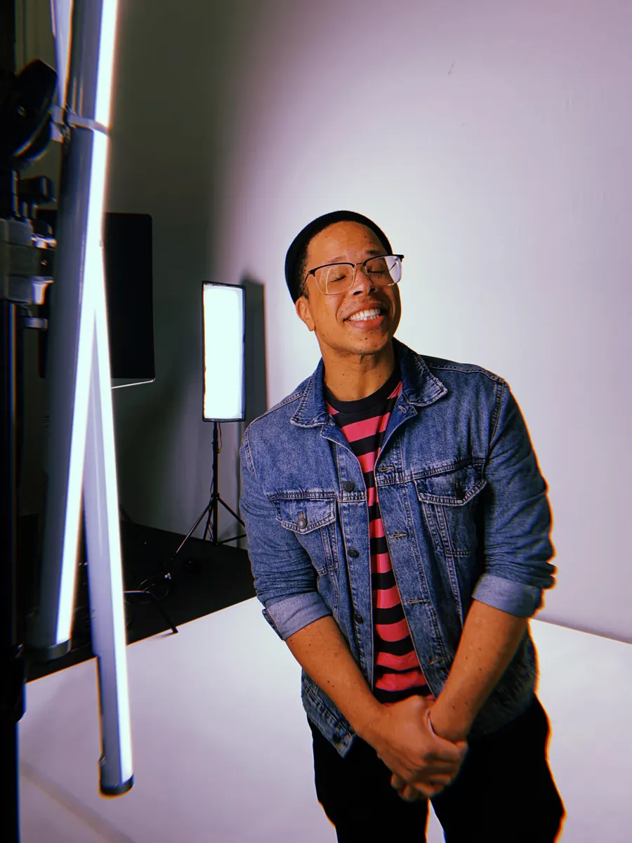 OKAY TK smiling in a denim jacket, studio portrait